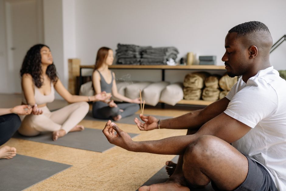 A diverse group practicing mindfulness meditation with incense in a serene indoor setting