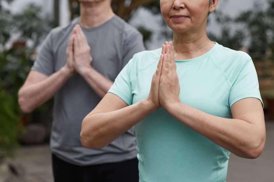 Senior couple in a meditative yoga pose outdoors, promoting wellness and a healthy lifestyle